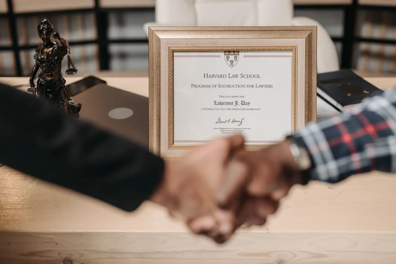 Handshake in front of a framed certificate
